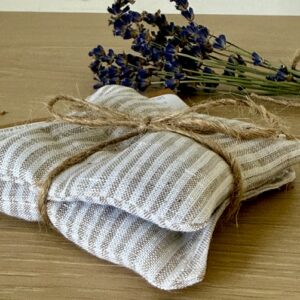 set of 2 lavender sachets tied up in string, with some dried lavender in the background