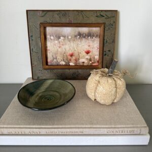 Fall vignette - beige coffee table book, fabric pumpkin, green pottery dish, vintage framed art
