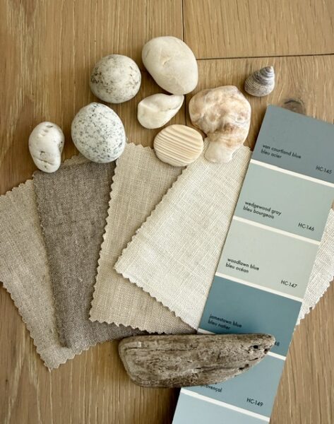 assortment of neutral linen fabric samples, strip of paint colours in blue tones and beach rocks