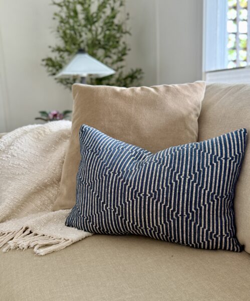 beige and navy pillows on sofa with textured throw